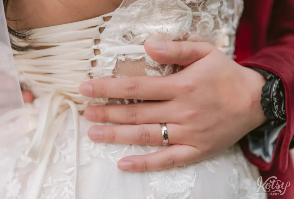 A close up shot of a grooms hand with wedding band around his bride's waist during their wedding at The Vue in Toronto