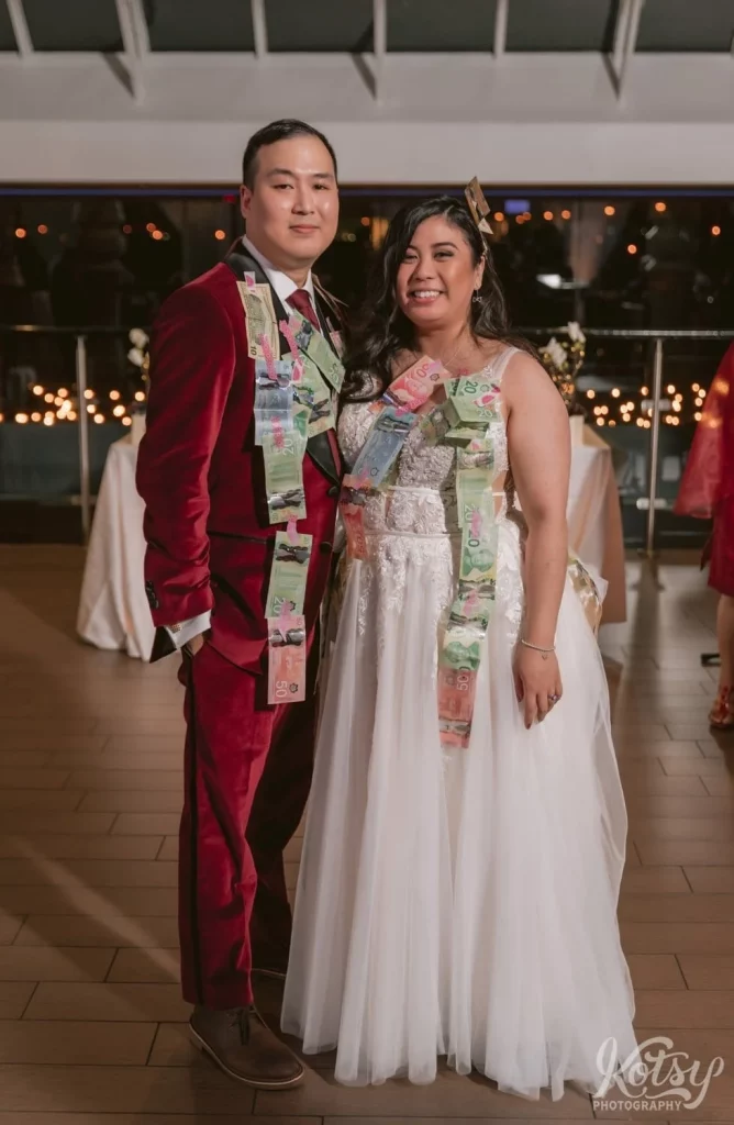 A bride and groom pose with money tapes to them after a money dance at The Vue Event Venue in Toronto