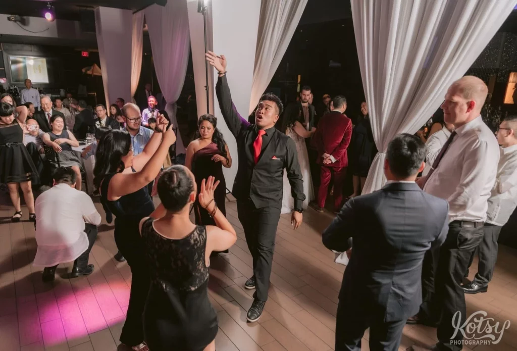 A man puts his hand up as he dances at a wedding reception in Toronto