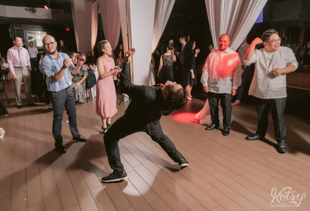 A man bends over backwards while playing air guitar at a wedding reception at The Vue Event Venue in Toronto