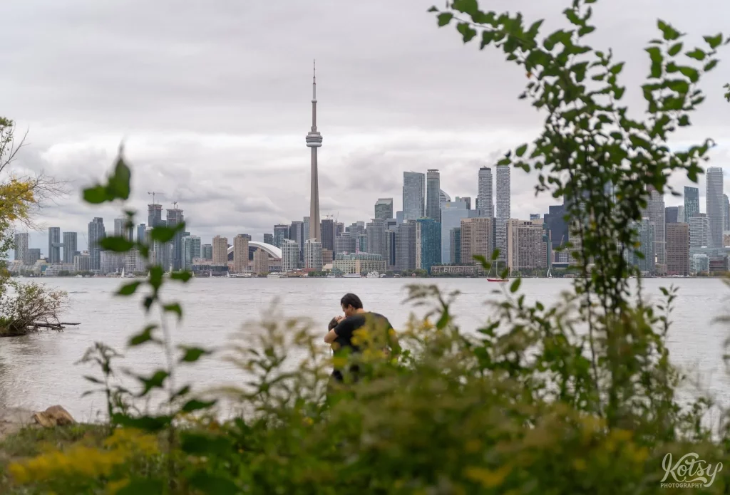 A couple kissing is seen through the bushes on a beach at Toronto Islands