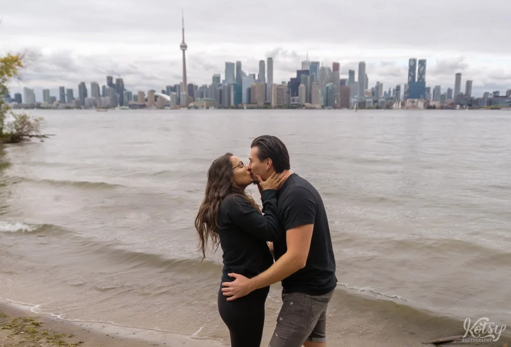 A couple kiss on a beach at Toronto Islands after getting engaged