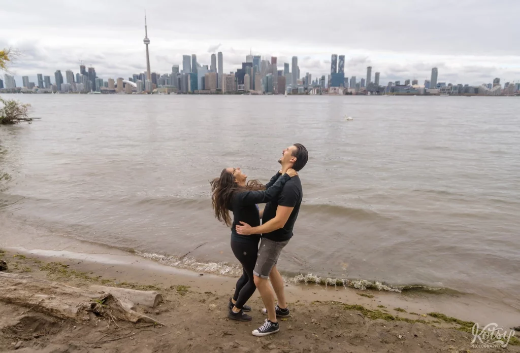 A couple laugh after their proposal on a beach at Toronto Islands