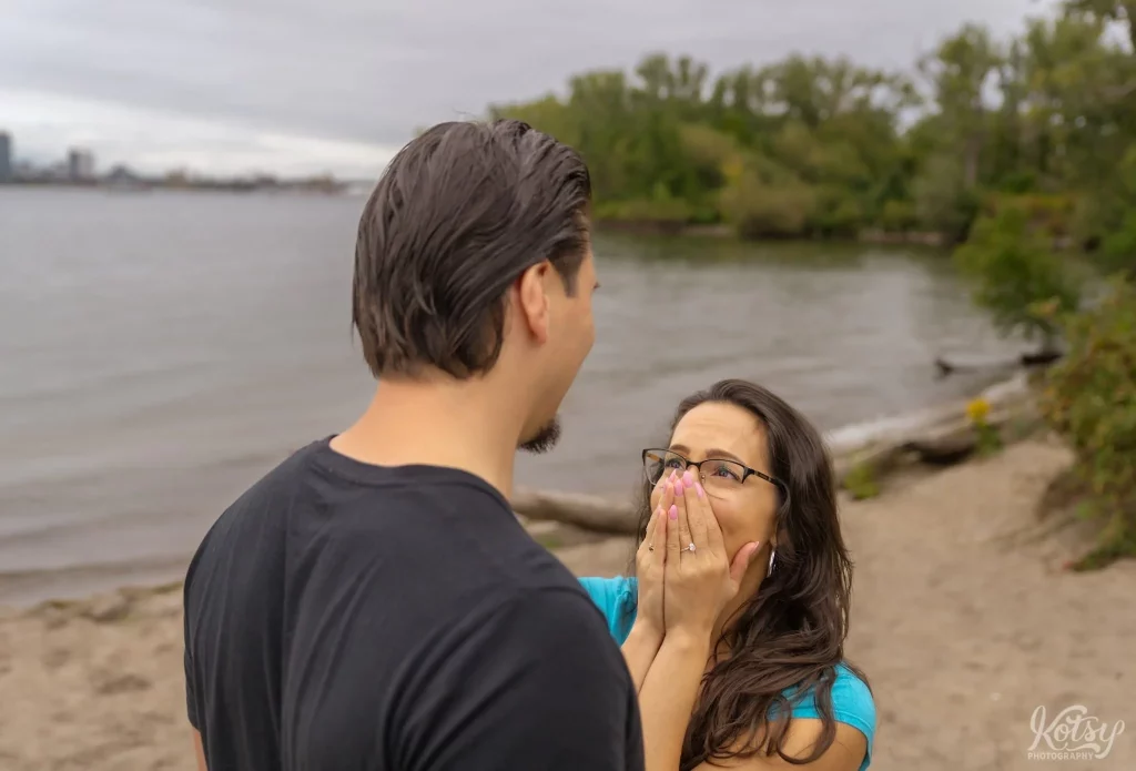 A woman covers her face in glee after a proposal at Toronto Islands