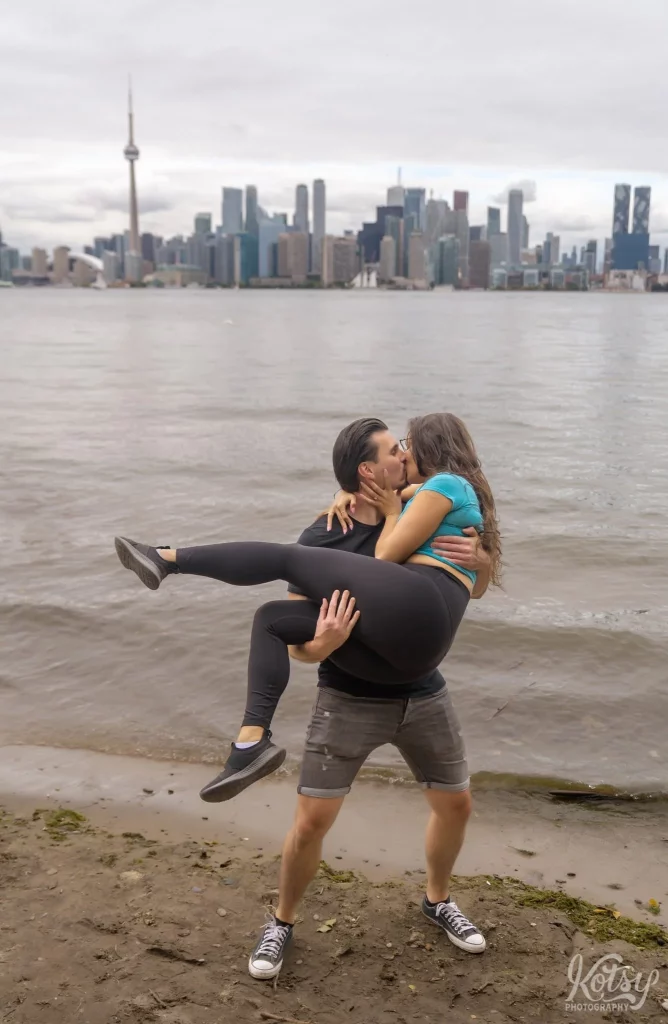 A man holds his new fiancé as he kisses her after their proposal on Toronto Islands