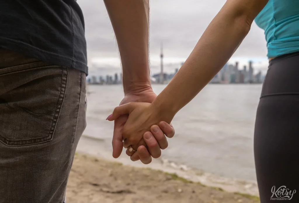 A close up of a couple holding hands on a beach at Toronto Islands