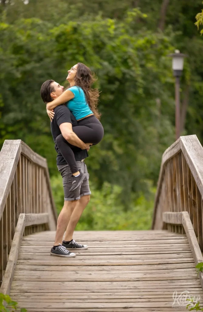 A man holds his new fiancé up as she smiles with glee after their proposal on Toronto Islands