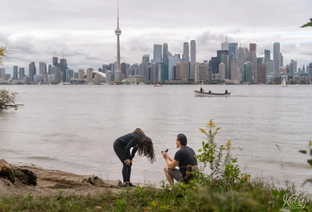 A woman reacts in total shock as her boyfriend proposes to her on one knee at Toronto Islands