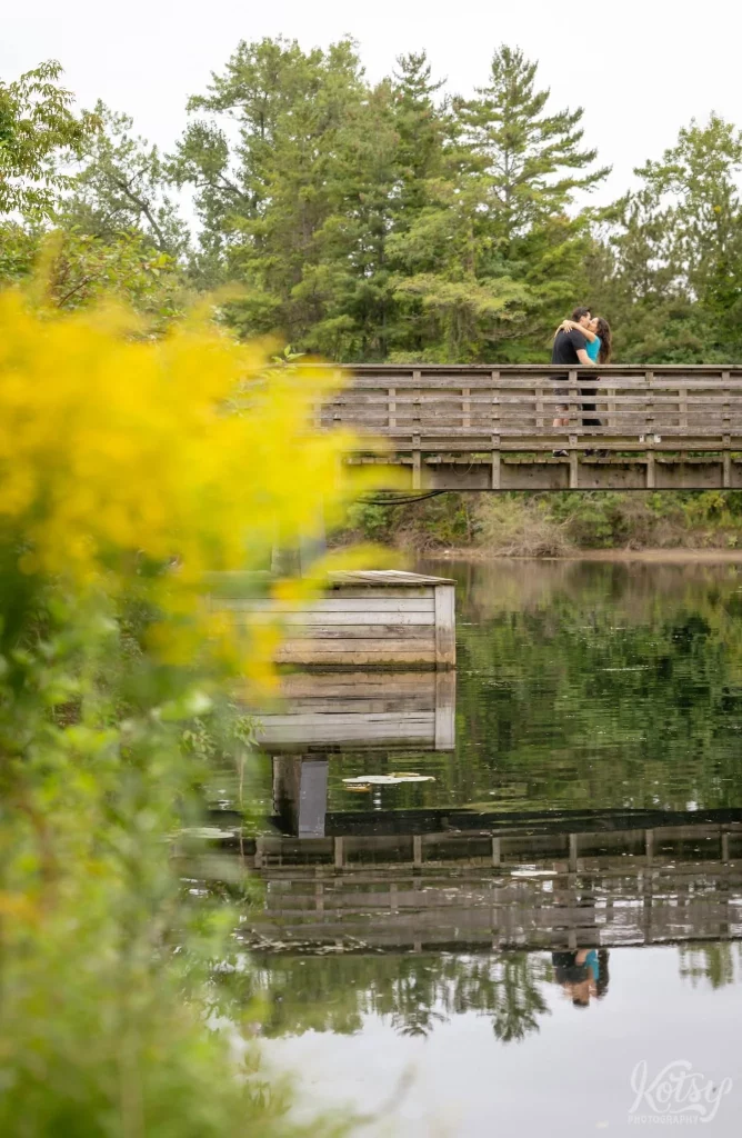 A couple kiss each other on a wooden bridge on Snake Island in Toronto