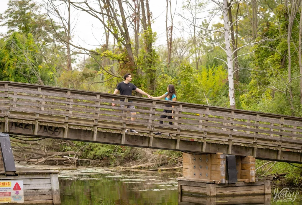 A man leads his fiancé across a wooden bridge on Snake Island in Toronto