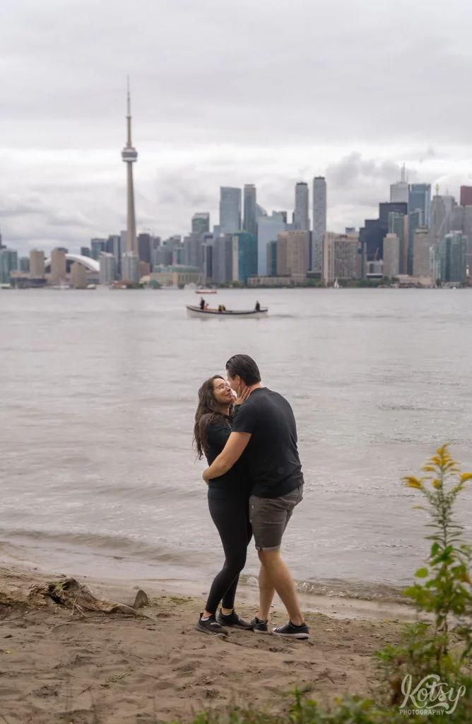 A couple touch noses on a beach at Toronto Islands after getting engaged