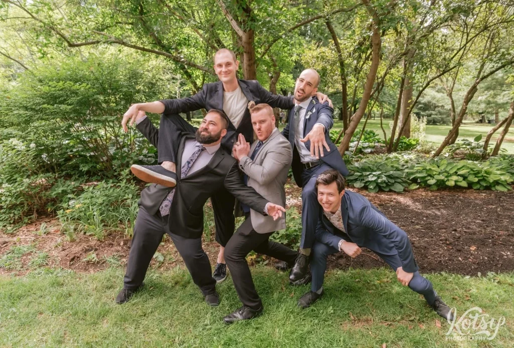 A groom poses with a group of friends like they're action movie stars