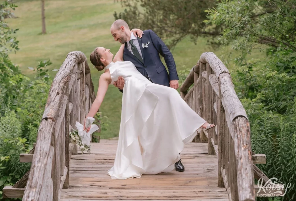 A groom dips his bride on a wooden bridge at Edwards Gardens in Toronto