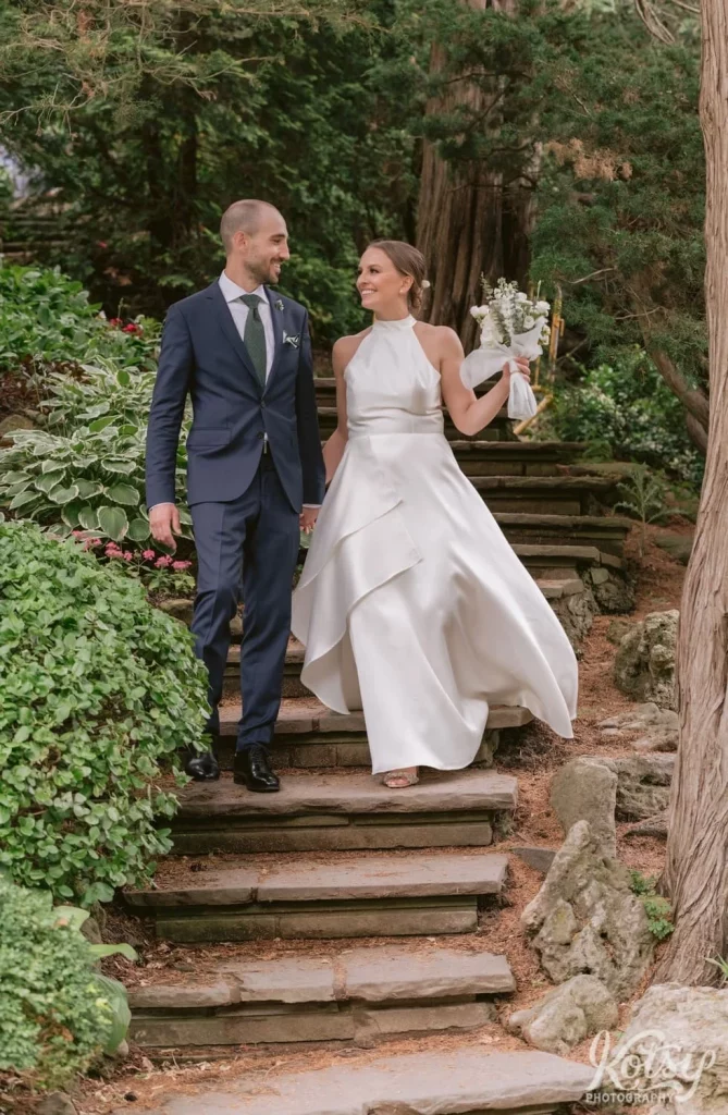 A bride and groom walk down a stone staircase at Edwards Gardens in Toronto