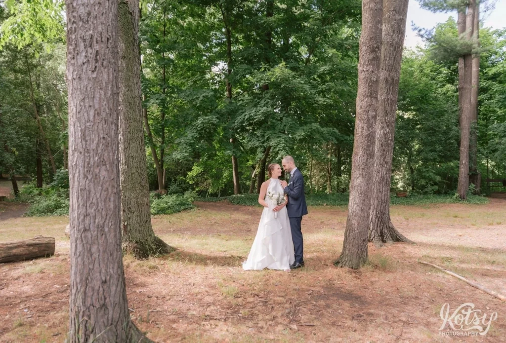A bride and groom gaze into each other's eyes in a forest at Edwards Gardens in Toronto