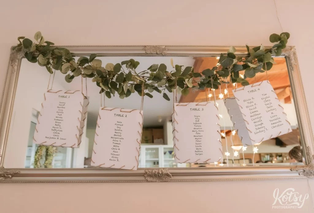 The seating plan for a wedding reception made up of paper and thin rope hanging from a vine
