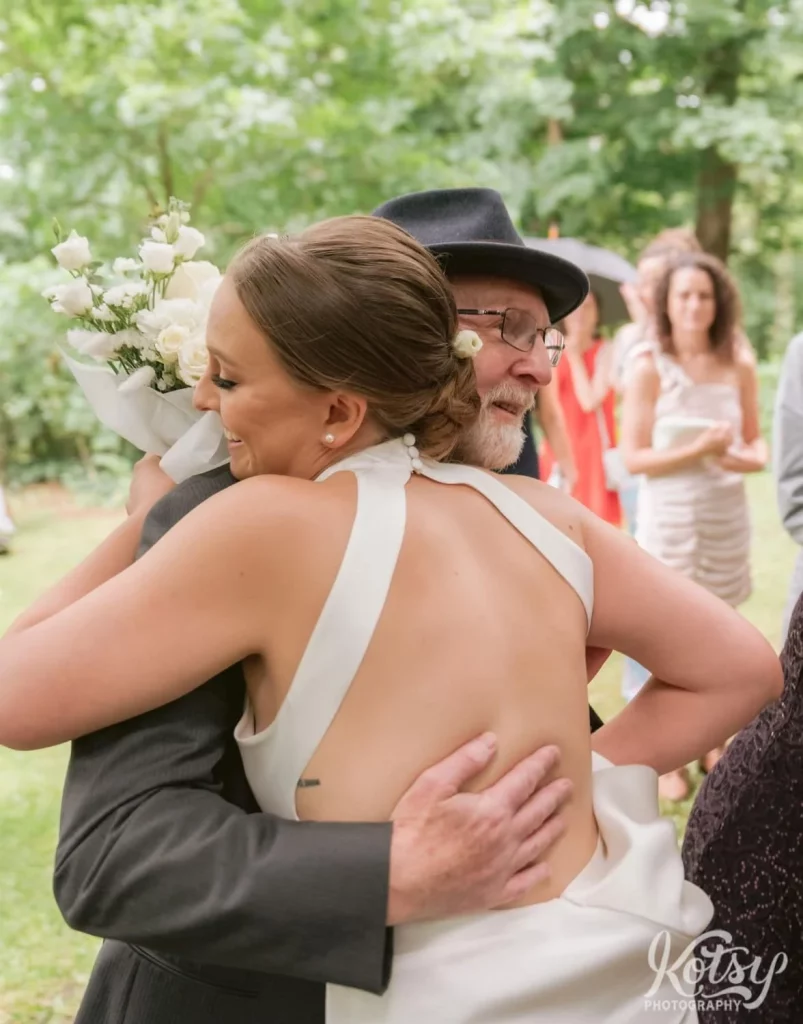 A bride hugs her father at the start of her wedding ceremony at Edwards Gardens in Toronto