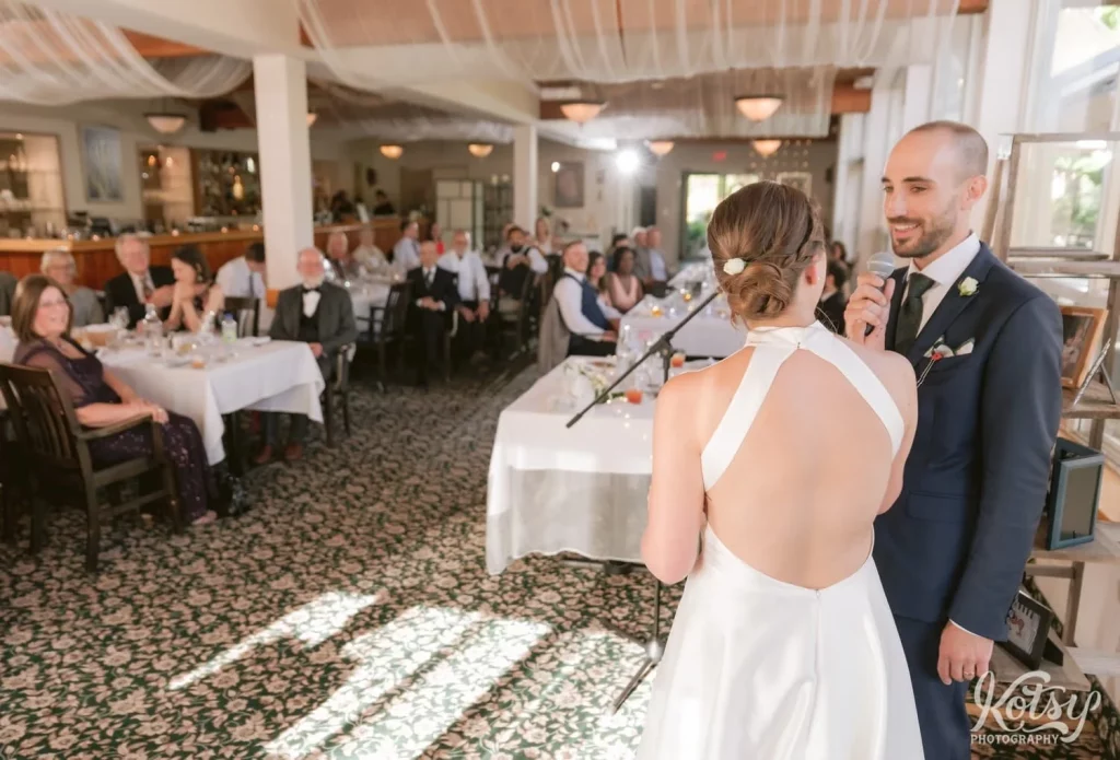 A groom makes a speech as her looks at his bride during their wedding reception at The Prague Restaurant in Scarborough