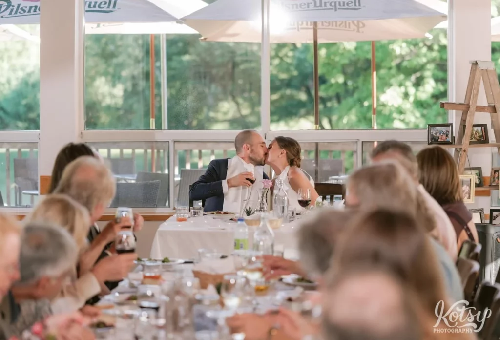 A bride and groom kiss at their dinner table during their wedding reception at The Prague Restaurant in Scarborough