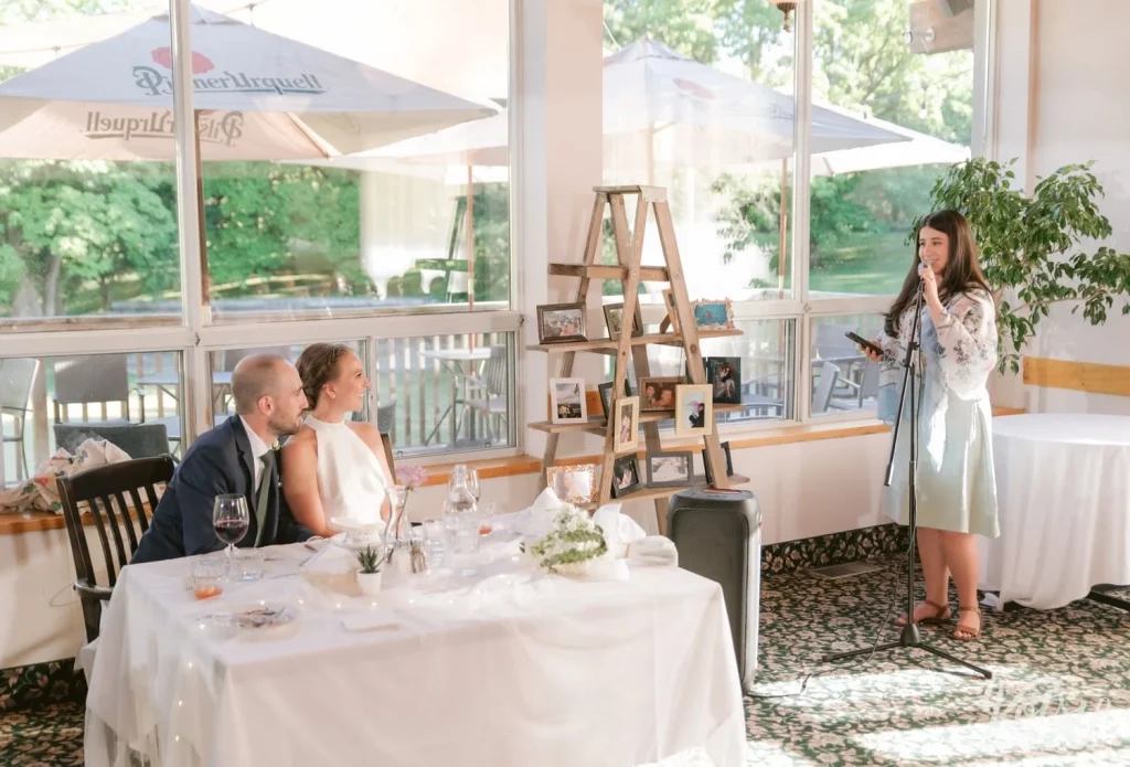 A wide shot of a woman making a speech to a bride and groom during their wedding reception at The Prague Restaurant in Scarborough