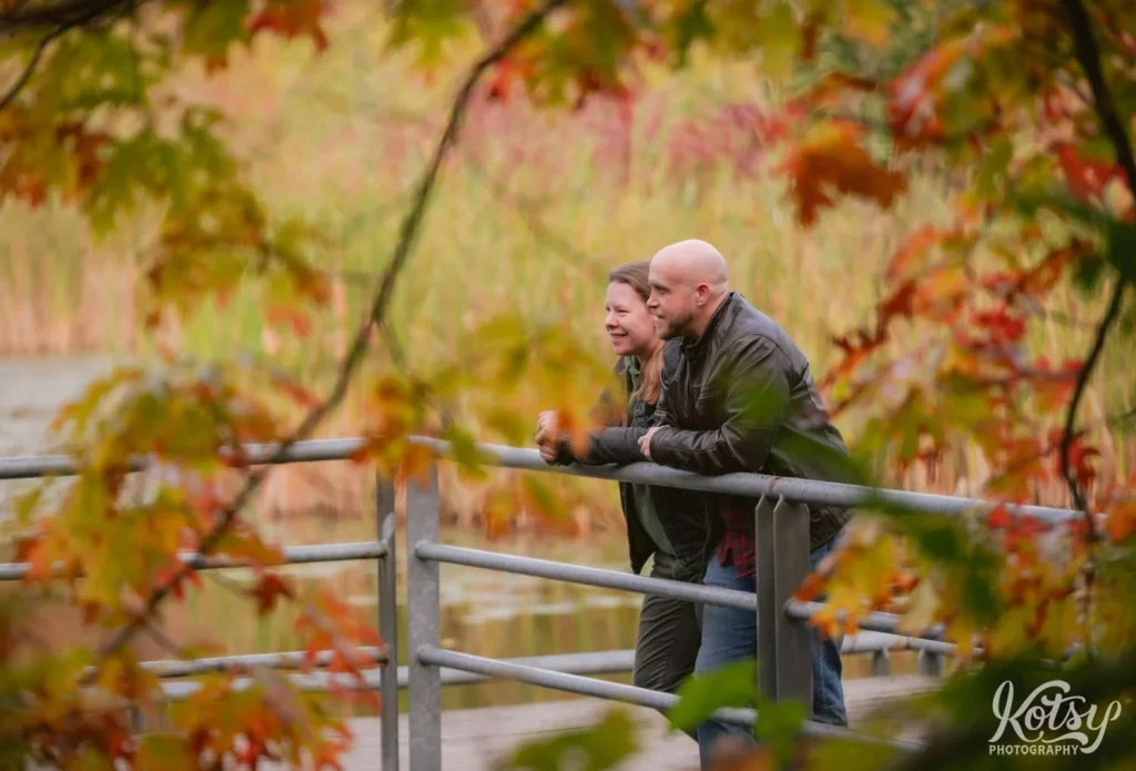 A couple take in the sights of fall colours while leaning on a hand rail in Don Valley Brick Works Park in Toronto