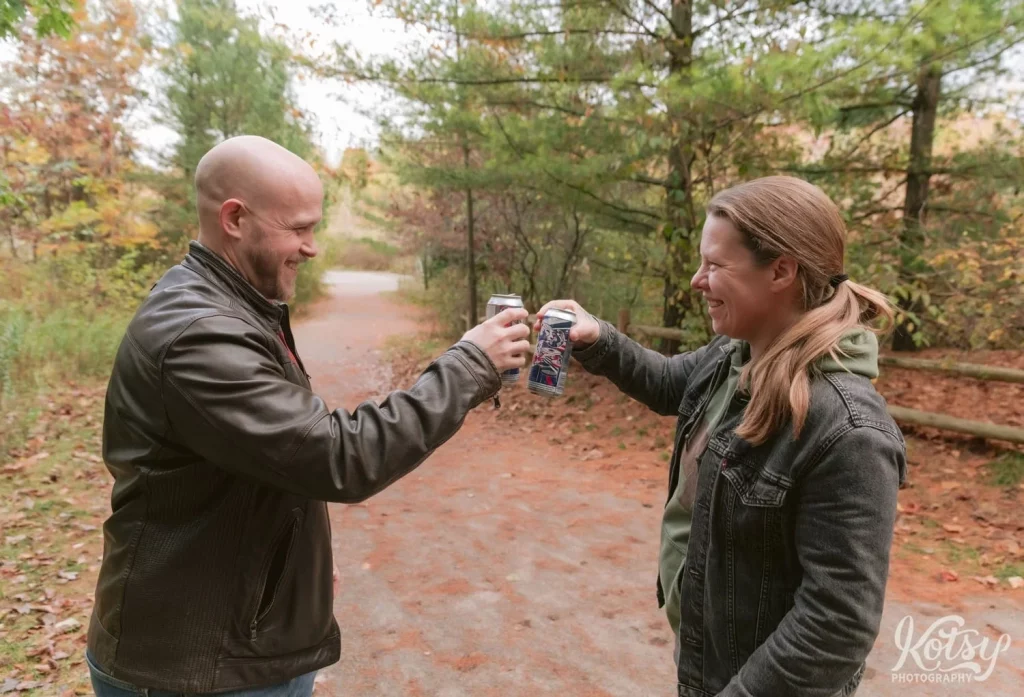 An engaged couple cheers their beers in a trail in the Don Valley Brick Works Park