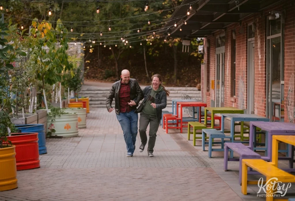A couple are all laughs as they run towards the camera at Evergreen Brick Works in Toronto