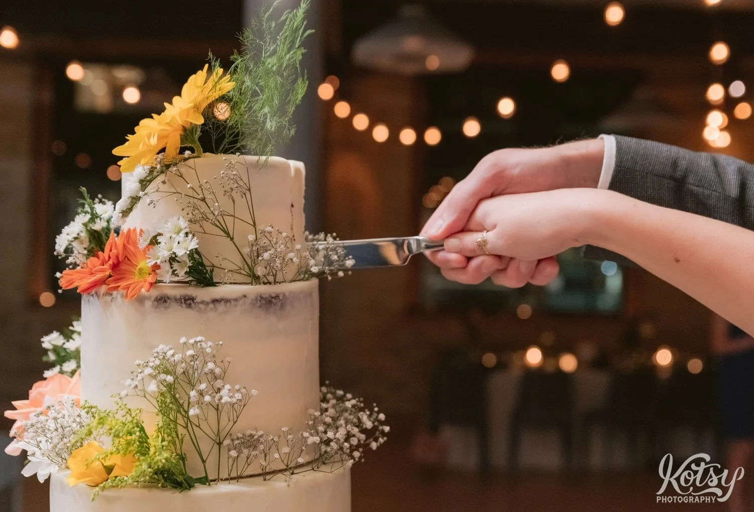 A close up shot of a pair of hands cutting a three tier wedding cake with a butter knife during a Second Floor Events wedding reception in Toronto, Canada.