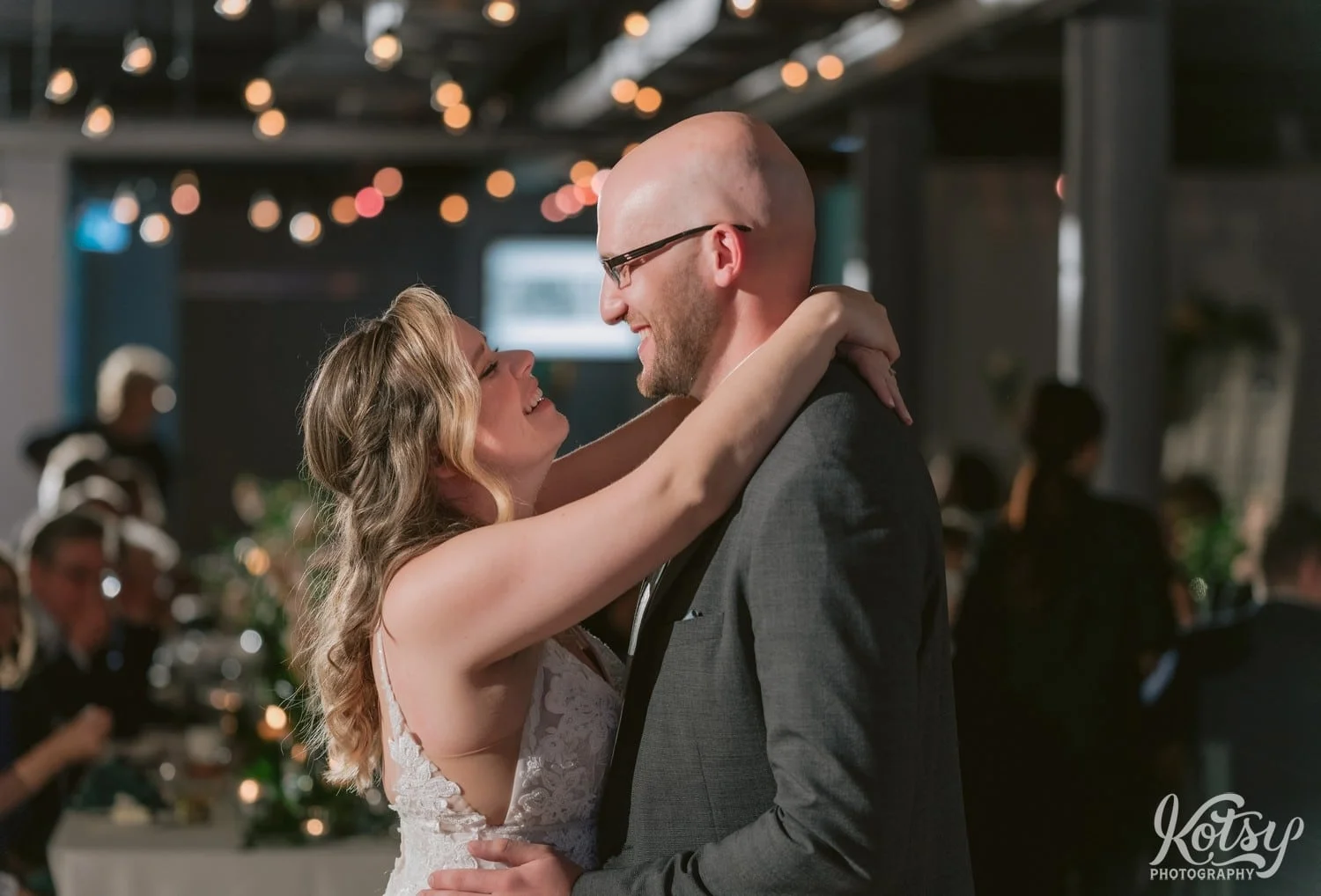 A really tight shot of a bride and white wedding gown and grooming gray suit looking at each other and smiling during their first dance at Second Floor Events wedding reception in Toronto, Canada.