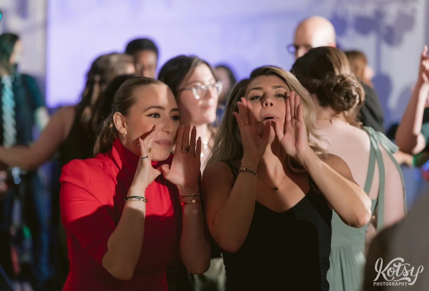 Two women are seen yelling something with arms around their mouths during a Second Floor Events wedding reception in Toronto, Canada.