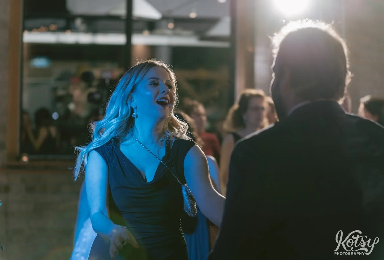 A woman in a green dress dances with her mouth open in excitement during a Second Floor Events wedding reception in Toronto, Canada.