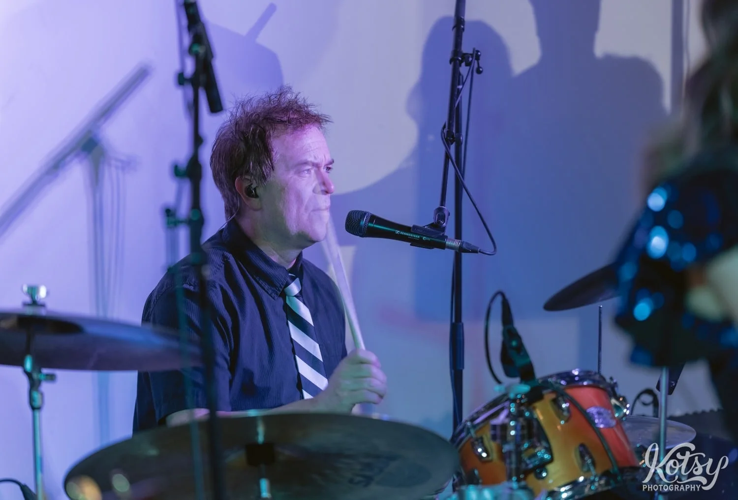 A drummer wearing a black shirt and striped tie plays the drums during a Second Floor Events wedding reception in Toronto, Canada.