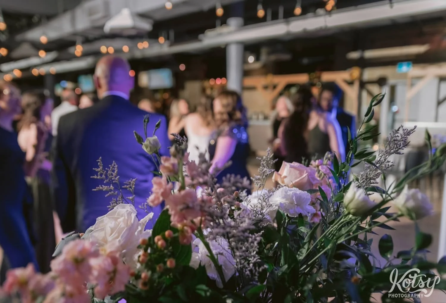 A close up shot of a bouquet of flowers with people dancing in the background out of focus during a Second Floor Events wedding reception in Toronto, Canada.