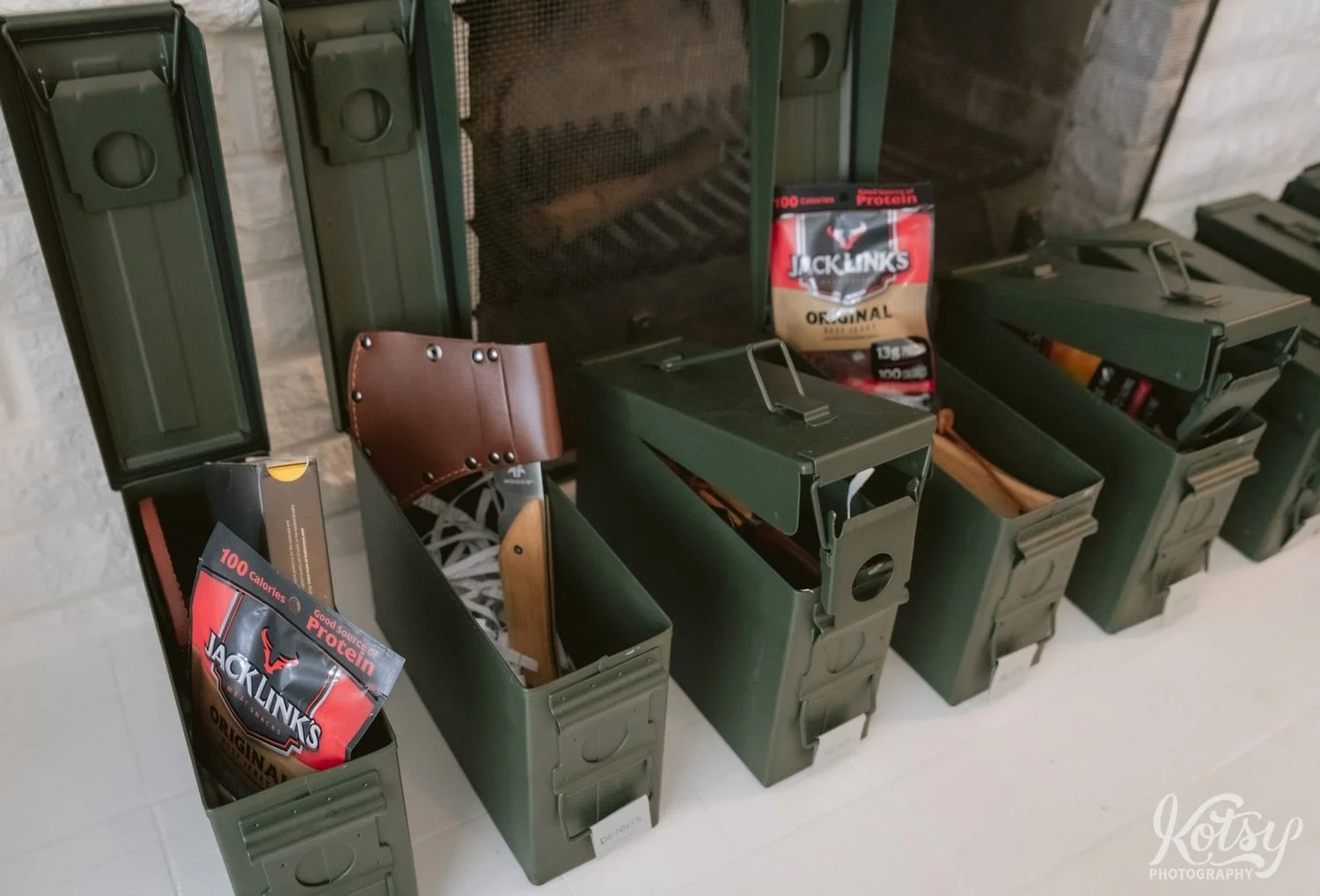 A row of ammo cans are seen with items like beef jerky and an ax as groomsmen gifts
