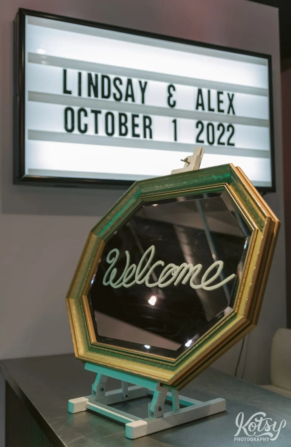 A mirror with the word welcome is seen in front of a marquee sign reading Lindsey and Alex October 1 2022. Photographed at second floor events in Toronto Canada