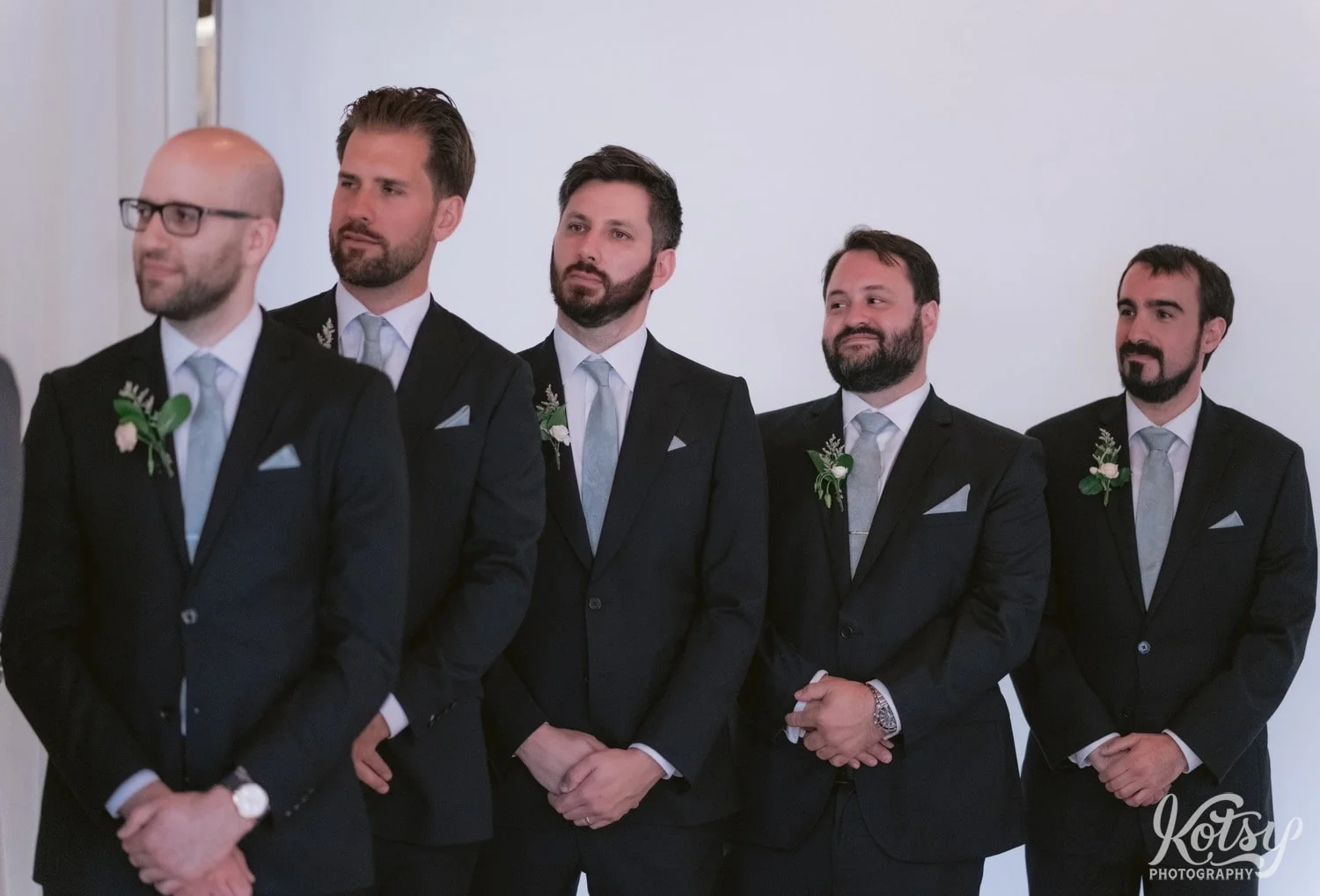 5 groomsmen wearing black suits smile while looking off camera during a Second Floor Events wedding ceremony in Toronto, Canada