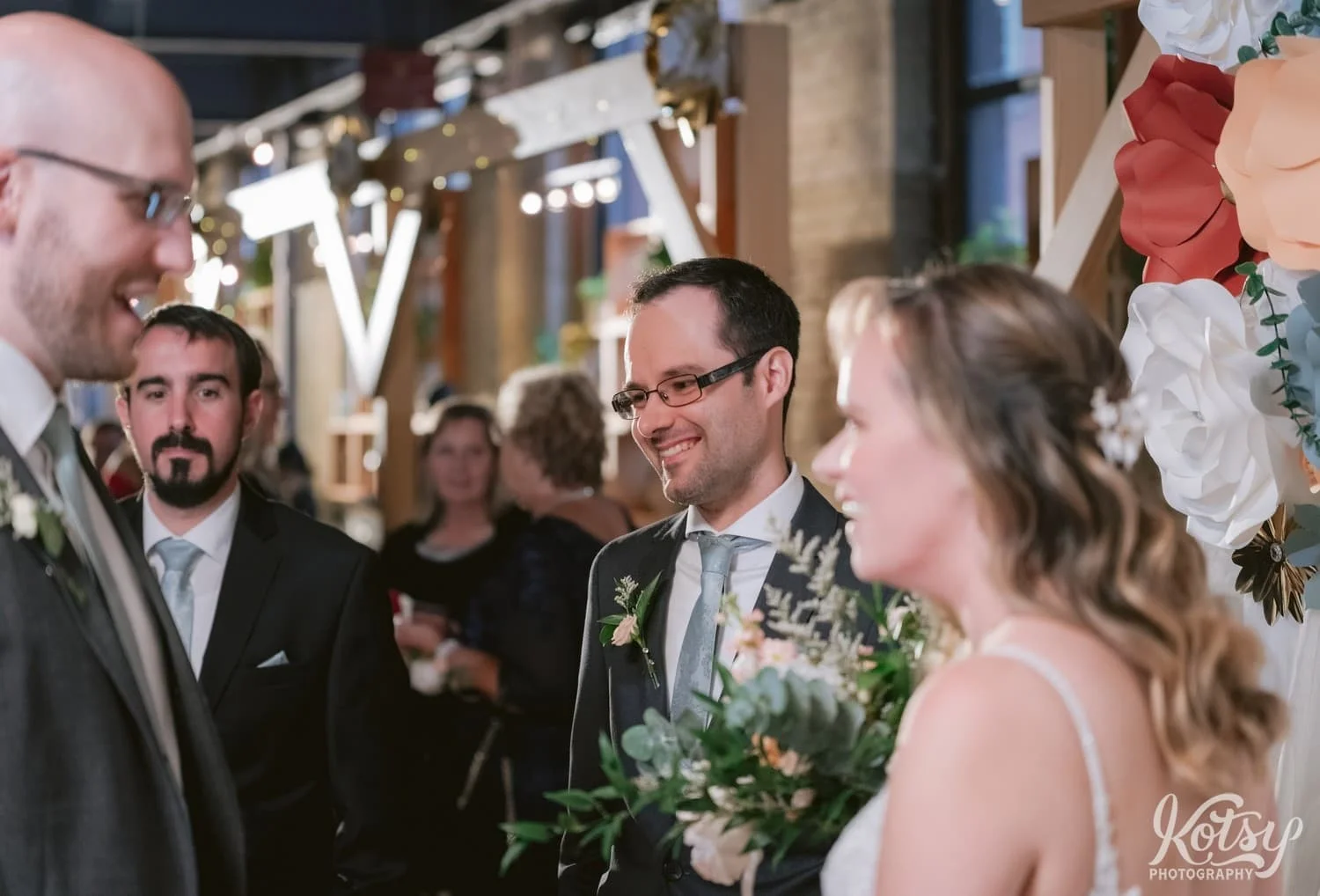 A man in a gray suit and green tie smiles to someone off camera during a Second Floor Events wedding reception in Toronto, Canada
