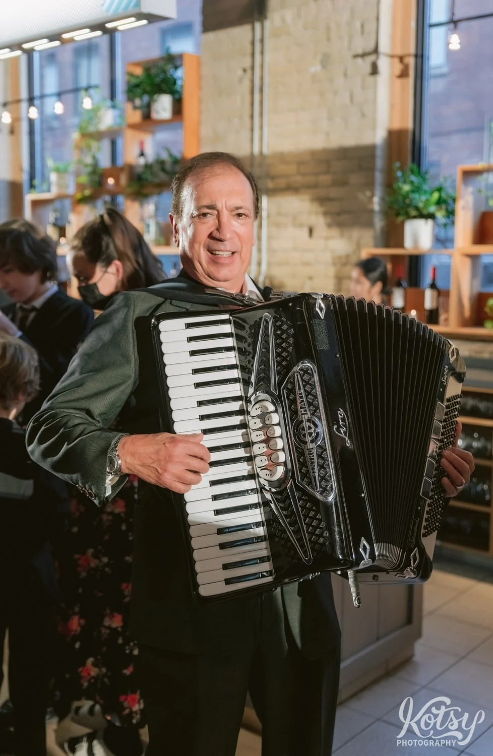 And accordion player poses for a photo while holding his accordion during a wedding reception at second floor events in Toronto Canada