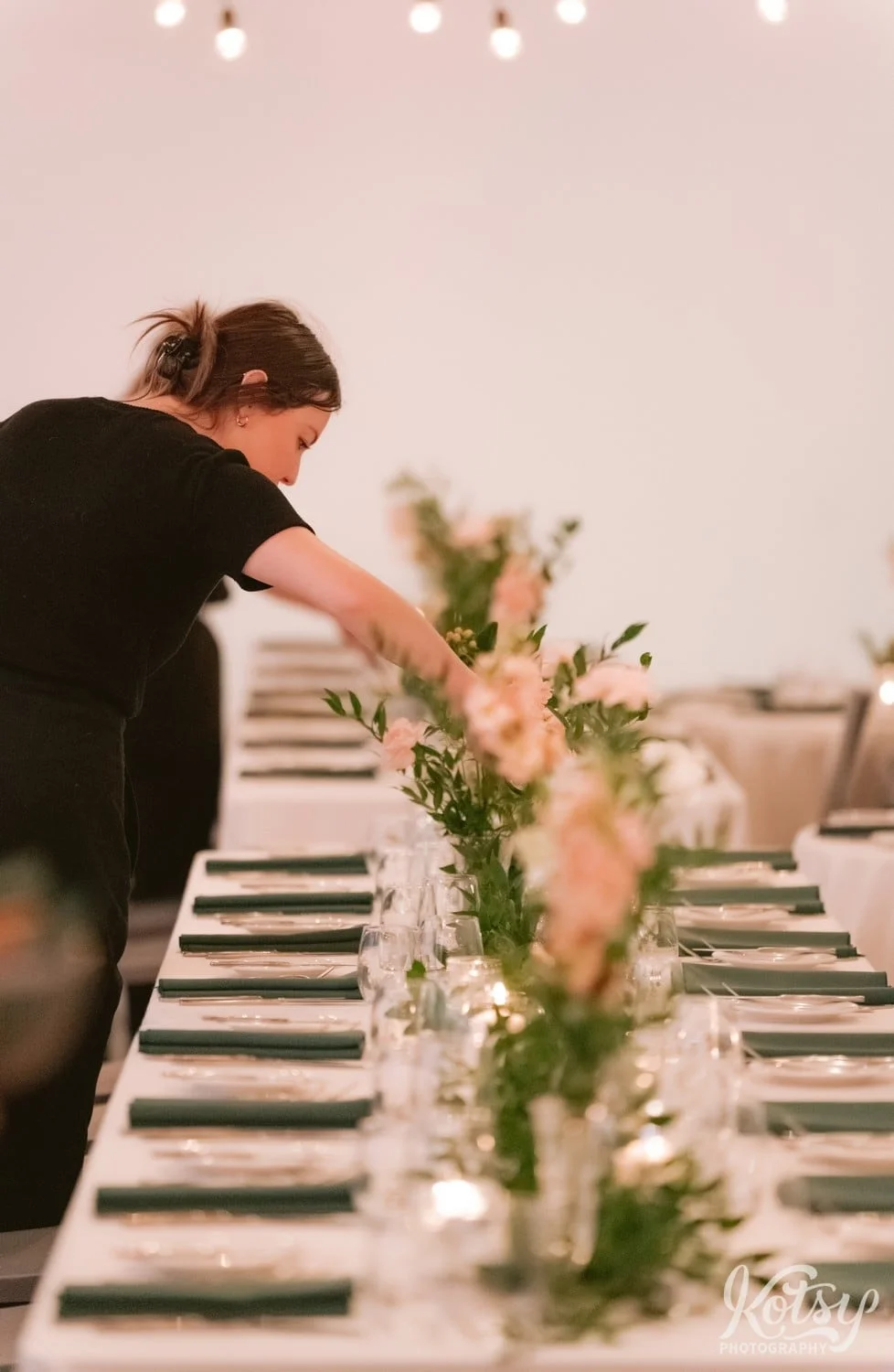 shot down a long table set up for guests. A woman is seen at the end lighting a candle. Photographed at second floor events in Toronto Canada