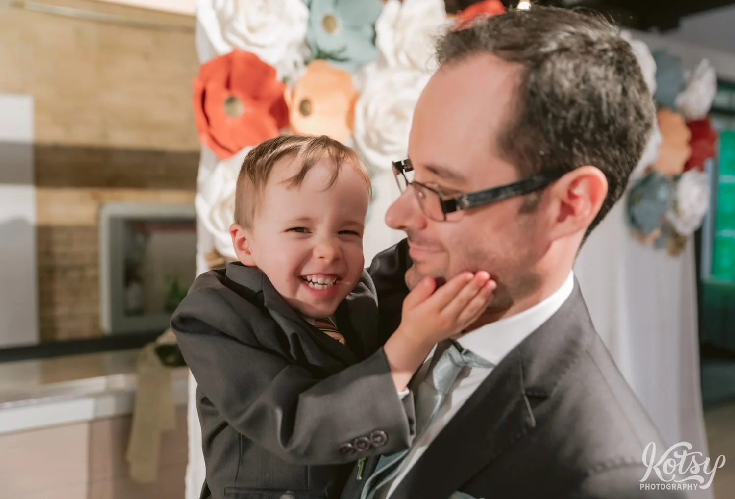 A child is seen smiling for the camera while placing his hand on his father's cheek during a Second Floor Events wedding reception in Toronto, Canada.