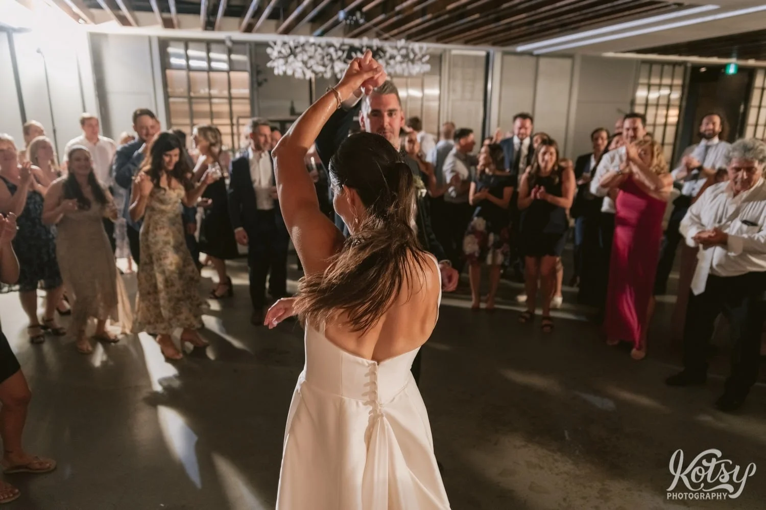 A bride's hand is raised by the groom during a dance at their Village Loft wedding reception in Toronto, Canada