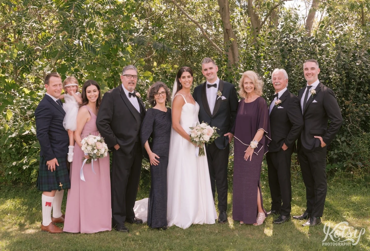 A bride and groom pose with their immediate families at Hunter's Point Wildlife Park in Toronto, Ontario, Canada
