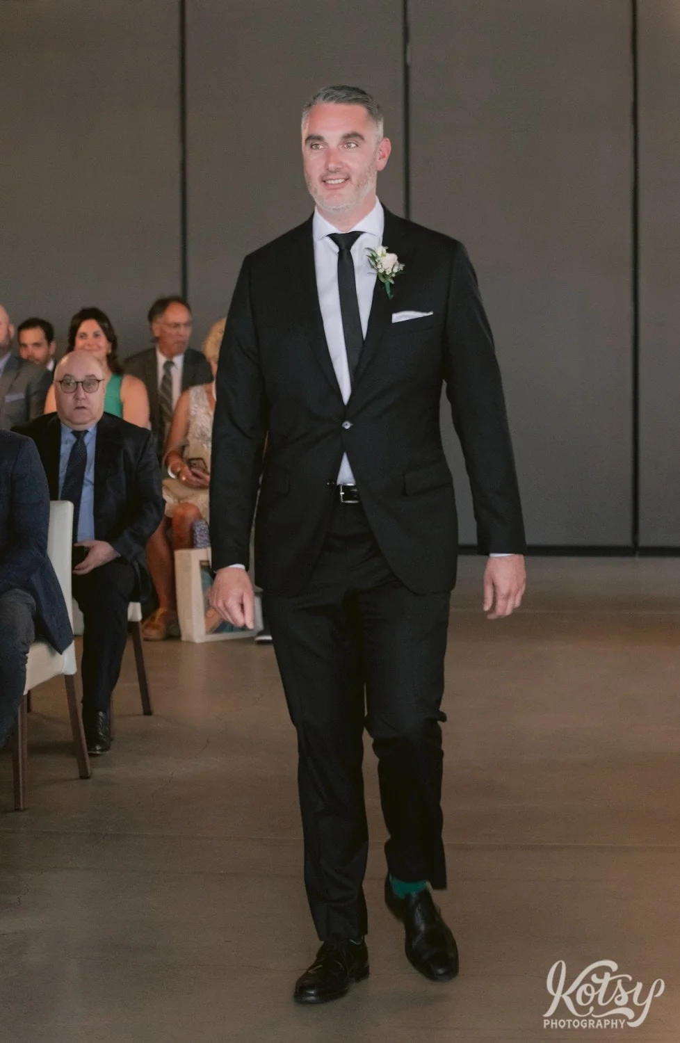 A full body shot of a best man walking down the aisle during a Village Loft wedding ceremony in Toronto, Canada