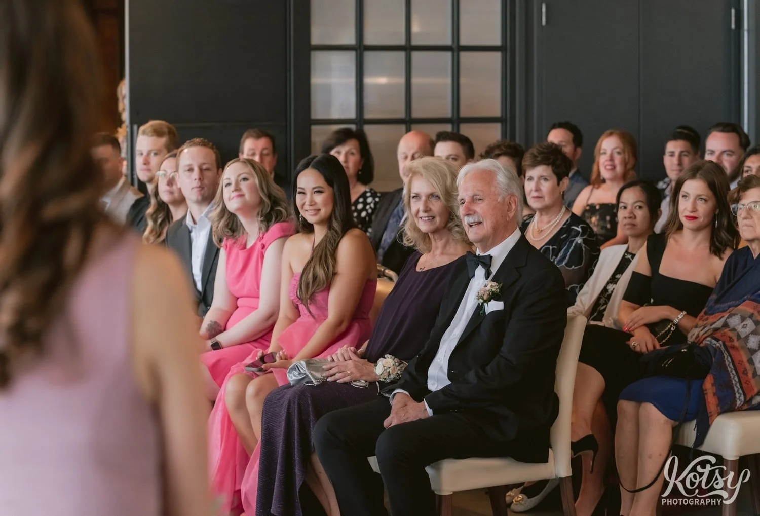 A shot of a groom's parents and many other guests watching a Village Loft wedding ceremony in Toronto, Canada