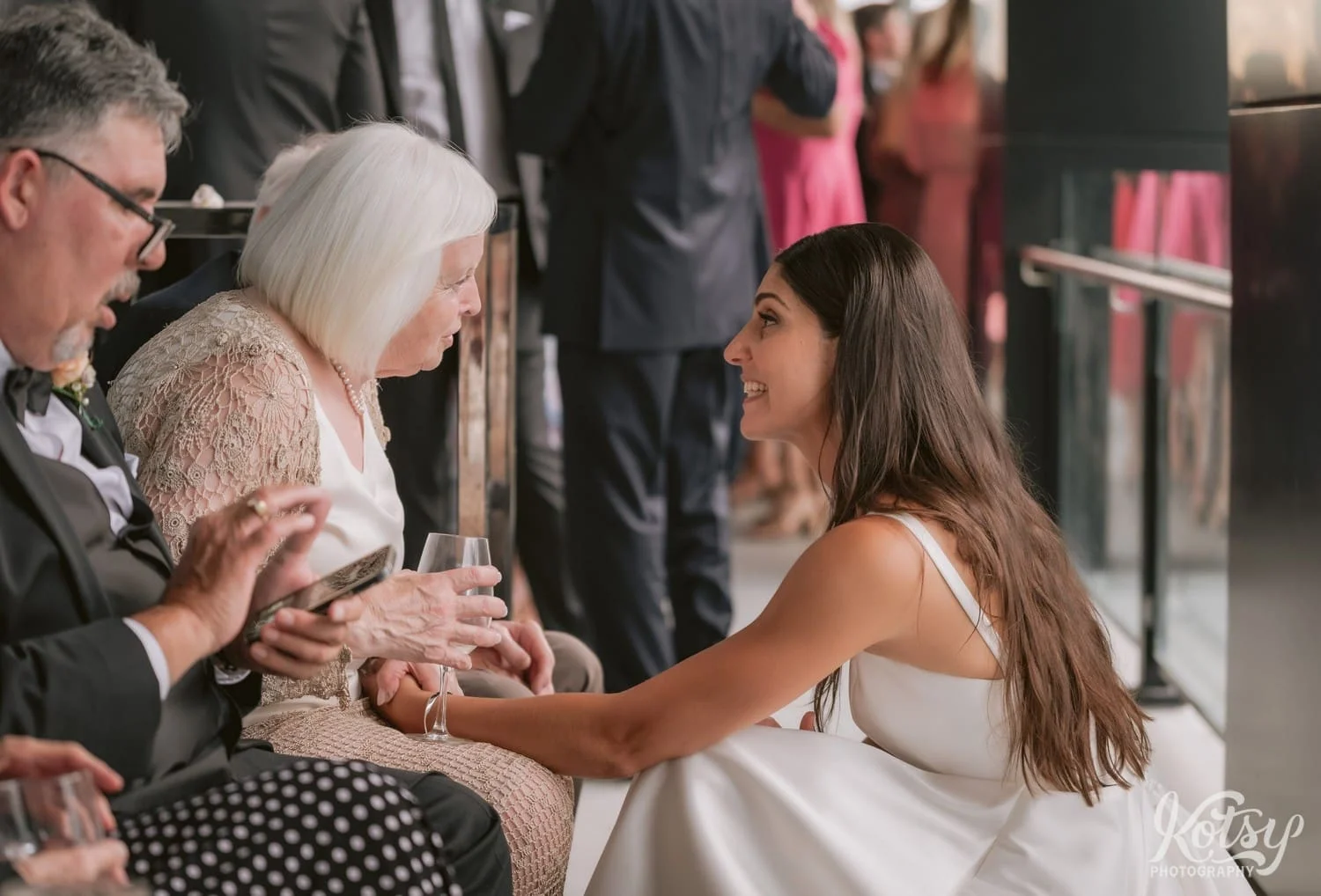 A bride holds an elderly woman's hand as she talks to her during her Village Loft wedding reception Loft in Toronto, Canada