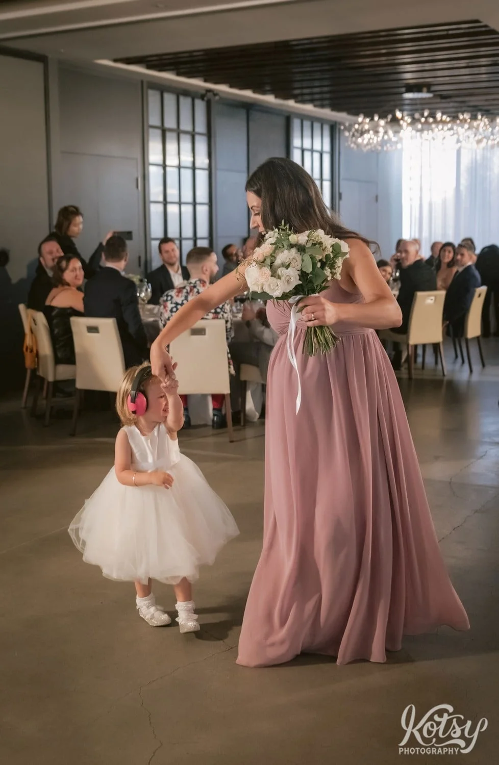 A woman in a pink dress spins the flower girl as they make their entrance during a Village Loft wedding reception in Toronto, Canada