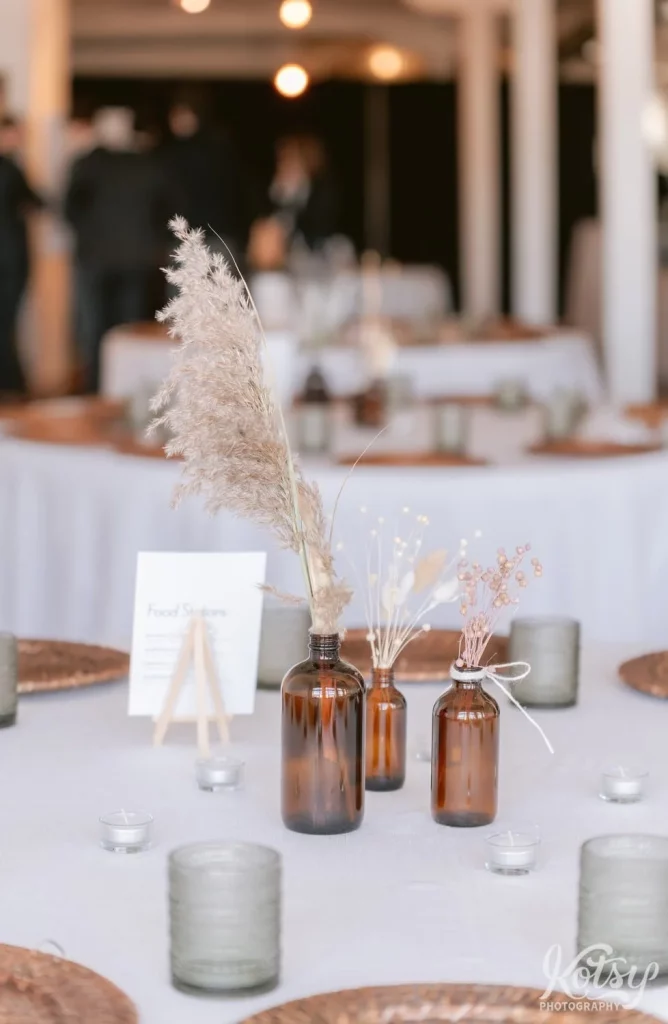 Pampas grass and baby's breath and brown bottles on a dinner table with gold plates