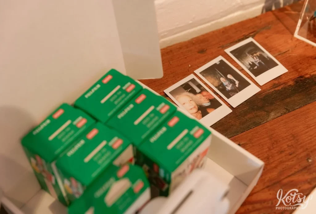 Three Polaroid Pictures are seen on a table with boxes of unopened film