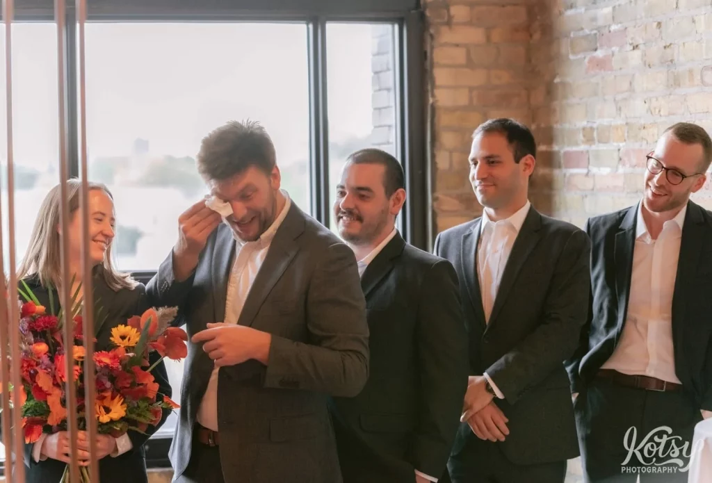 A groomsmen wiped tears from his eyes with a tissue as the others react during a Burroughes Building wedding ceremony in Toronto, Canada